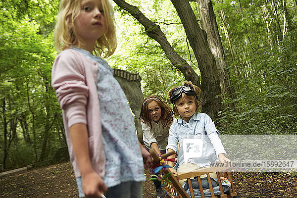 Kinder mit Handwagen spielen im Wald