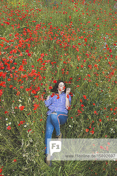 Young woman lying in poppy field