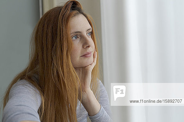 Portrait of serious young woman looking out of window