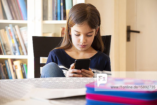 Mädchen macht Hausaufgaben mit Smartphone