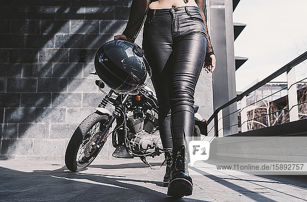 Junge Frau mit Motorradhelm  die von ihrem Motorrad weggeht