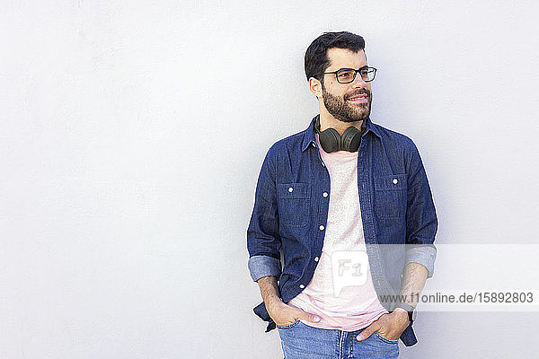 Porträt eines lächelnden Mannes mit drahtlosen Kopfhörern  der in die Ferne schaut
