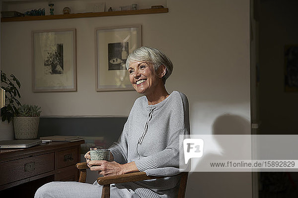 Porträt einer glücklichen älteren Frau  die sich bei einer Tasse Tee zu Hause entspannt