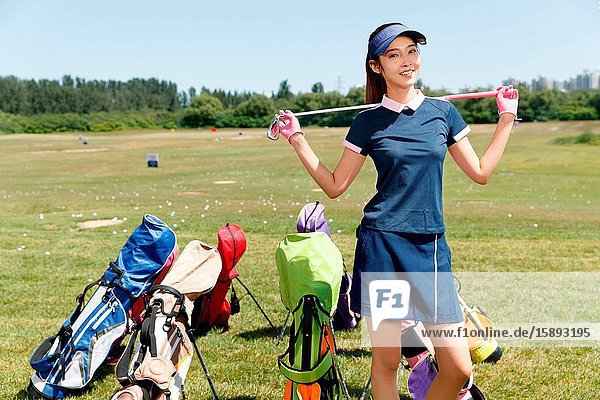 Young woman carrying clubs stood beside a golf bag