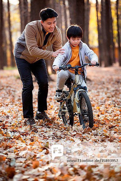 Father and son of outdoor learning to ride a bicycle