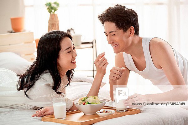 Glückliches junges Paar beim Frühstück im Bett