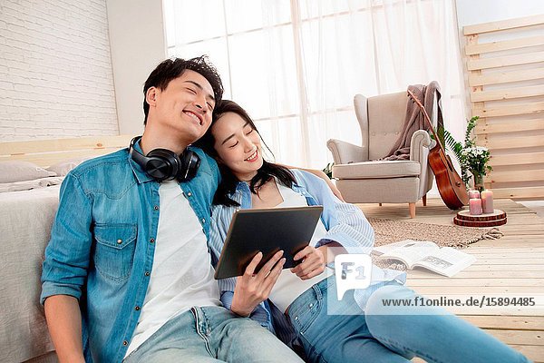 The young couple sitting on the floor use tablet computers