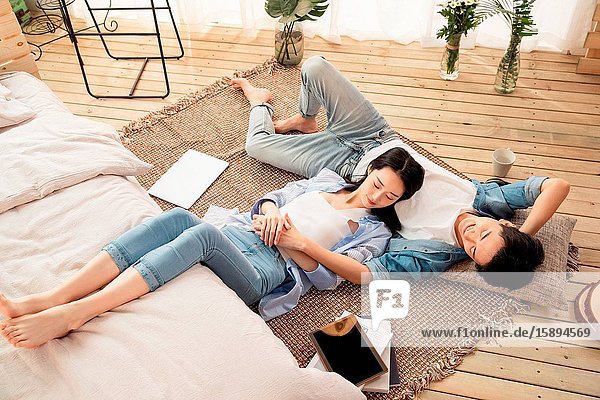 Happy lovers lying on the carpet to enjoy an afternoon