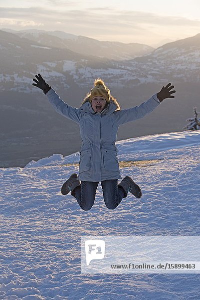 Woman jumping in winter on sunset.