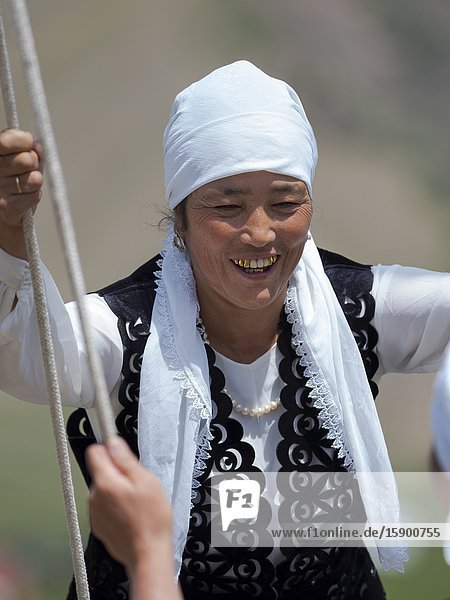 Woman in traditional garb having fun on a swing. Folk Festival commemorating the origin myth the Tien Shan Maral (Tian Shan wapiti) an origin myth of the Kyrgyz tribes. Near Tasch Baschat Naryn region. Asia Central Aisa Kyrgyzstan