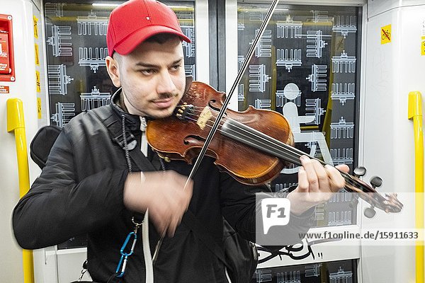Berlin Germany. Street musician performing his music inside an U-Bahn train to earn a bit of coin and cash.