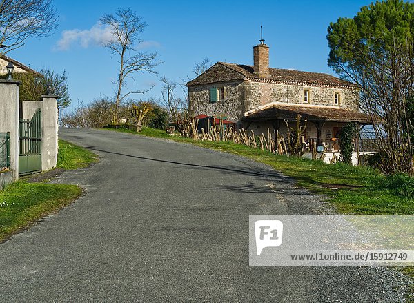 Stone house and empty road in the countryside near Tourtres Lot-et-Garonne Department Nouvelle Aquitaine France.