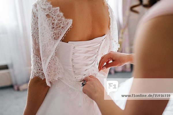 Dress up the bride in a wedding dress with corset and lacing.