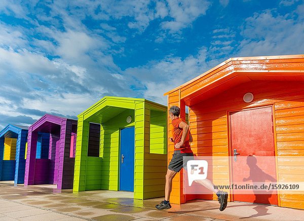 Mature jogger running past beach huts at Seaton Carew on the north east coast of England. Unite Kingdom.