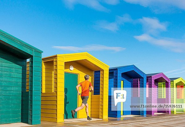 Mature jogger running past beach huts at Seaton Carew on the north east coast of England. Unite Kingdom.