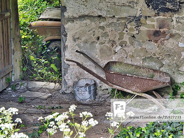 Abandoned wheelbarrow and rusty Peugeot 403 car Lauzun Lot-et-Garonne Department Nouvelle Aquitaine France.