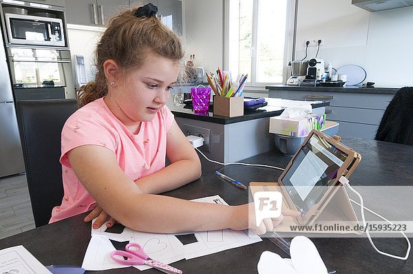 France  Loiret (45)  Covid-19 French lockdown on 04/27/2020  young girl of 7 years old in CE1 during virtual school class at home using tablet remote connection with her teacher and comrades.
