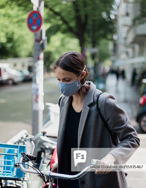 Woman with mask and bicycle.