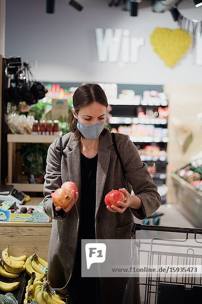 Woman in mask buying fruits at grocery store.