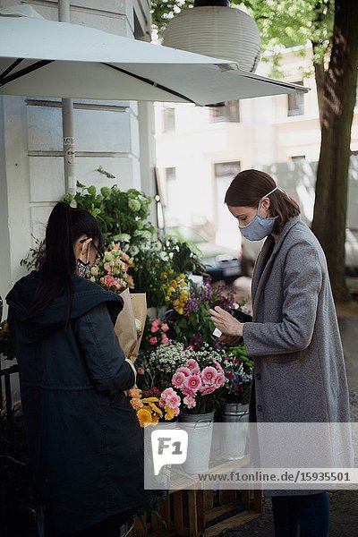 Woman with mask buying flowers.