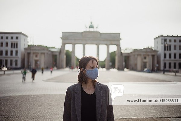 Woman with mask walking in Berlin in an empty Brandenburg gate.