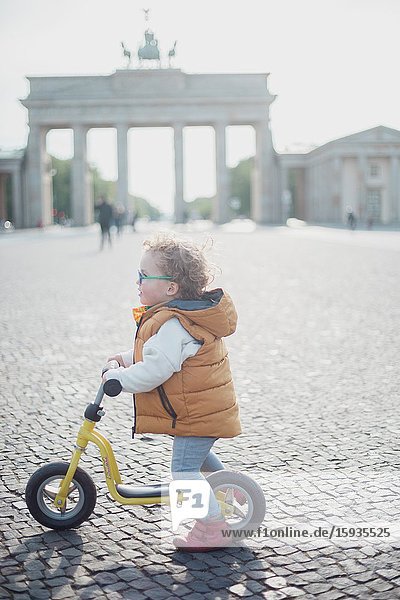 Little boy 2-3 Years old with bicycle and mask in front of Brandenburg gate in Berlin.