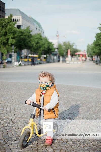 Little boy 2-3 years old with mask and bicycle in Berlin.