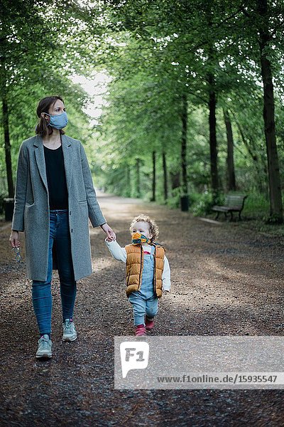 Mother and son walking in the park with mask during corona time.