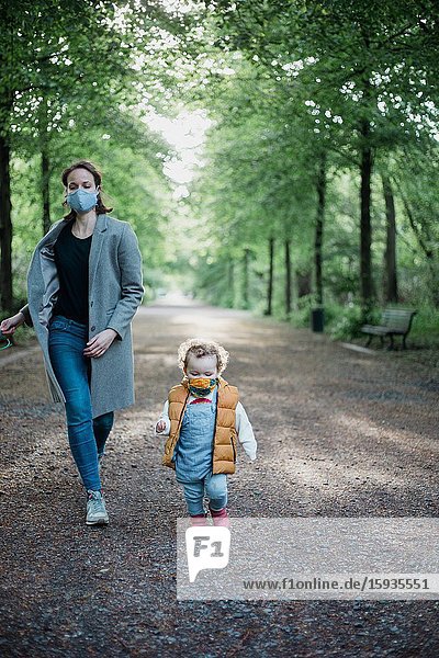 Mother and son walking in the park with mask during corona time.