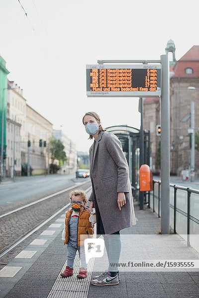 Mother and son with mask waiting for the bus.
