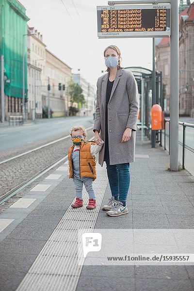 Mother and son with mask waiting for the bus.