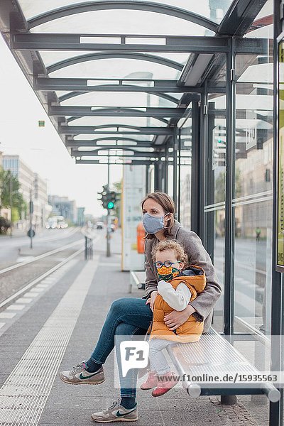 Mother and son with mask waiting for the bus.