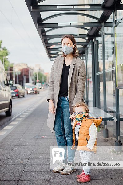 Mother and son with mask waiting for the bus.