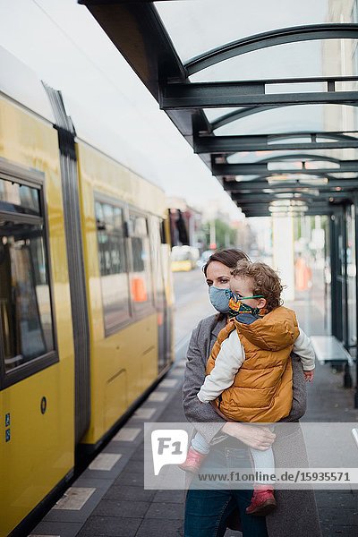 Mother and son taking public transport with mask during corona days.