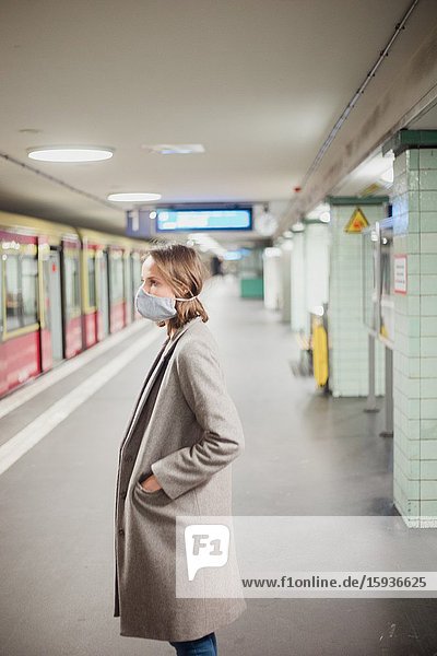 Woman waiting for the underground with mask during Corona days.