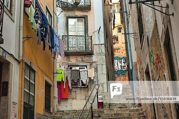 Narrow streets with laundry hanging to dry and graffiti in Alfama neighbourhood Lisbon Portugal.