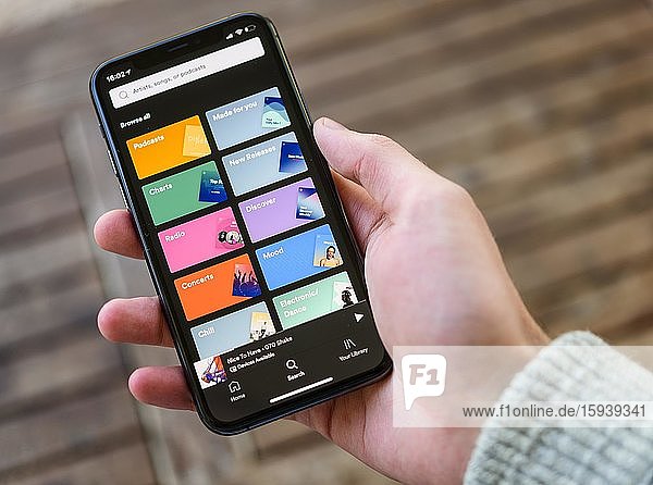 Hand holds iPhone 11 with Spotify App on display  music streaming  iOS  Smartphone  Germany  Europe