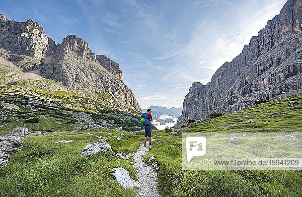 Hiker  mountaineer on a path between rocky mountains  Sorapiss circuit  behind mountain Punte Tre Sorelle  Dolomites  Belluno  Italy  Europe