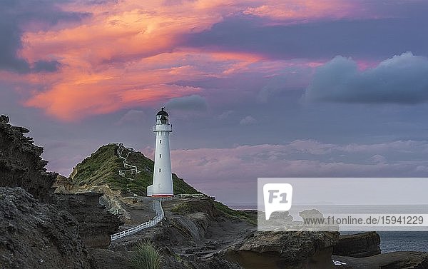 Leuchtturm im Abendlicht unter rosafarbenem Wolkenhimmel auf den Felsklippen am Castlepoint  Lavafels  Masterton  Wellington  Neuseeland  Ozeanien