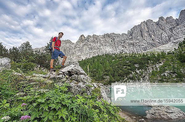 Hiker stands on a rock at turquoise green Sorapis lake  Lago di Sorapis  Dolomites  Belluno  Italy  Europe