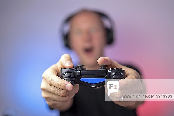 Gamer with headphones and gamepad having a lot of fun  Gamepad in the hand  Germany  Europe