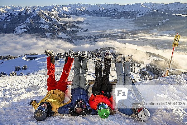 Skiers lie in the snow and stretch their legs in the air  snow-covered mountains  chairlift in the ski area SkiWelt Wilder Kaiser Brixental  Brixen im Thale  Tyrol  Austria  Europe