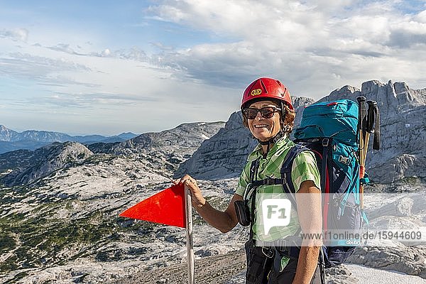 Bergsteigerin mit Rucksack und Helm blickt glücklich in die Kamera  Route von Simonyhütte zur Adamekhütte  felsiges alpines Gelände  Salzkammergut  Oberösterreich  Österreich  Europa