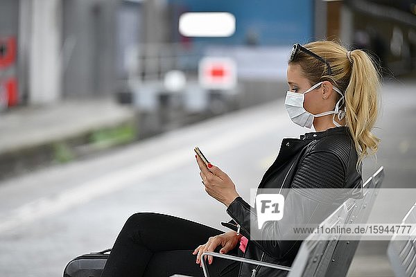 Woman with face mask  waiting for train  on mobile phone  corona crisis  main station  Stuttgart  Baden-Württemberg  Germany  Europe