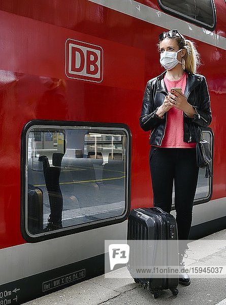 Frau mit Mundschutzmaske  wartet auf Zug  am Handy  Corona-Krise  Hauptbahnhof  Stuttgart  Baden-Württemberg  Deutschland  Europa
