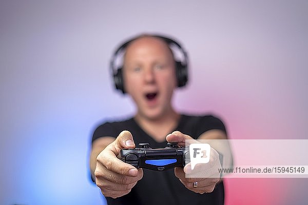Spieler mit Kopfhörer und Gamepad hat viel Spaß  Gamepad in der Hand  Deutschland  Europa