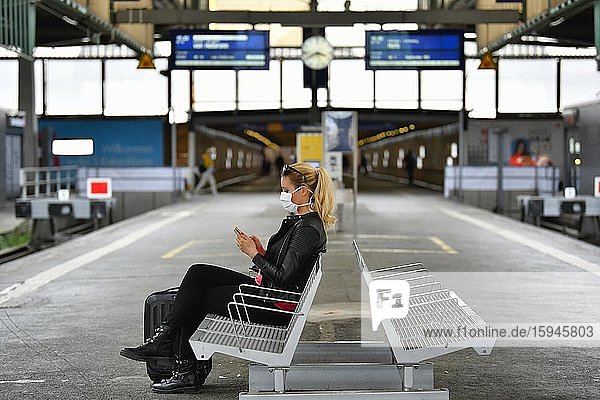 Frau mit Mundschutzmaske  wartet auf Zug  am Handy  Corona-Krise  Hauptbahnhof  Stuttgart  Baden-Württemberg  Deutschland  Europa