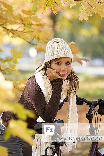 Porträt  junge Frau  Jugendliche im Herbst  gestützt auf Fahrrad  lächelnd  Oberösterreich  Österreich  Europa