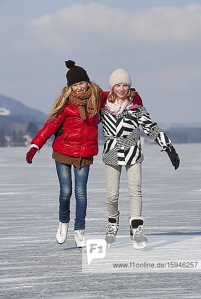 Young happy girls ice skating at a lake  14 years  Irrsee  Salzkammergut  Upper Austria  Austria  Europe