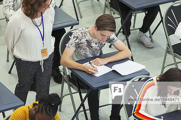 High school teacher supervising students taking exam in classroom